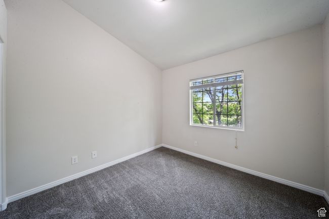 Spare room featuring dark colored carpet and lofted ceiling | Image 26