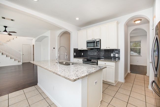 Kitchen with light tile patterned flooring, a sink, stainless steel appliances, and granite counters | Image 12