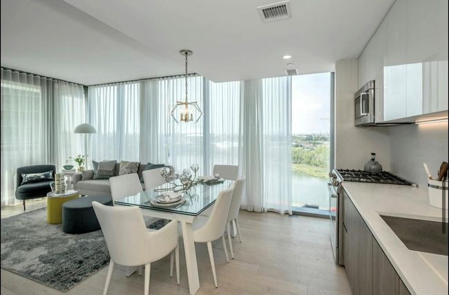 Dining area with a chandelier, expansive windows, and light wood-style floors | Image 6