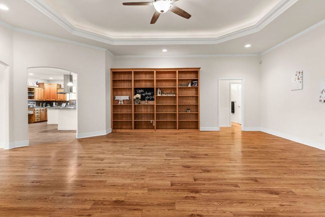 Unfurnished living room with a tray ceiling, arched walkways, a ceiling fan, recessed lighting, and light wood finished floors | Image 7