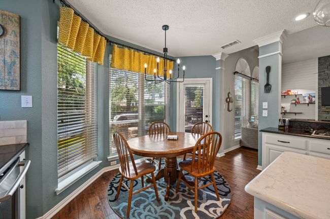 Dining room featuring a textured ceiling, dark wood finished floors, a chandelier, and a textured wall | Image 12