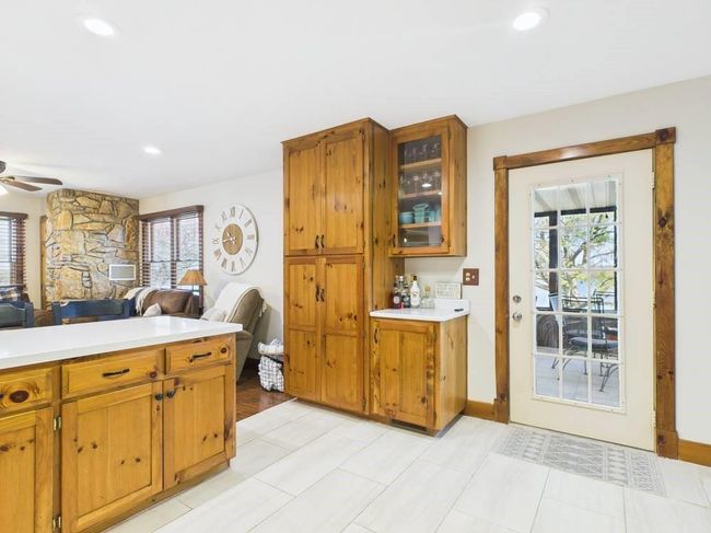 Kitchen featuring open floor plan, light countertops, brown cabinetry, and ceiling fan and view to covered deck | Image 42