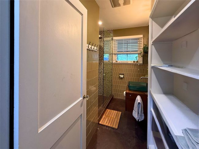 Full bathroom with tile walls, a tile shower, tile patterned flooring, vanity, and wainscoting | Image 10