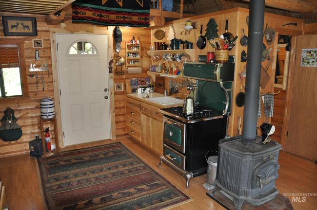 Entrance foyer with a wood stove, wood finished floors, and wooden walls | Image 9