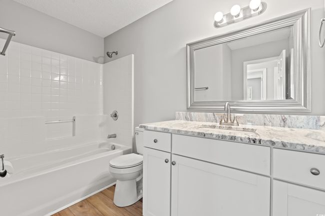 Full bathroom featuring vanity, shower / tub combination, wood finished floors, and a textured ceiling | Image 21