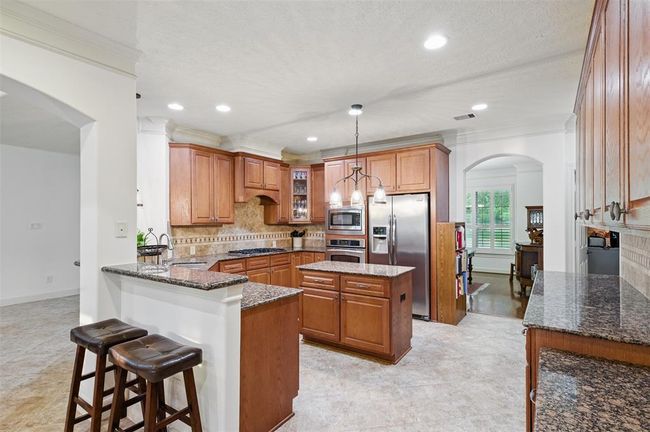 The kitchen features an island, 42" cabinets, granite countertops, stainless steel appliances and a walk-in pantry. | Image 17