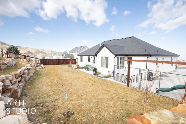 Rear view of property featuring a mountain view, a patio, and a lawn | Image 47