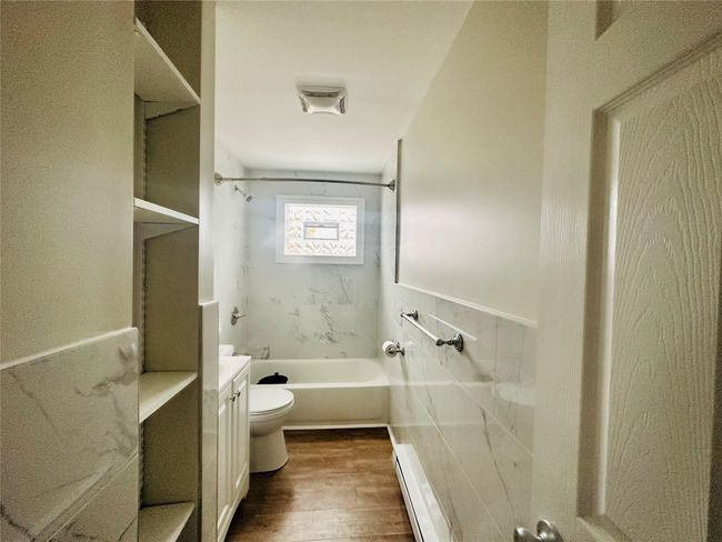 Full bathroom with vanity, tiled shower / bath combo, a baseboard radiator, hardwood / wood-style floors, and toilet | Image 8