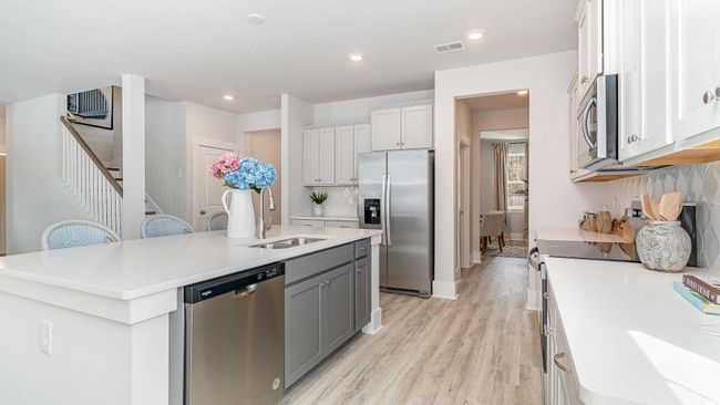 Kitchen featuring stainless steel appliances, a sink, a center island with sink, light countertops, and recessed lighting | Image 13