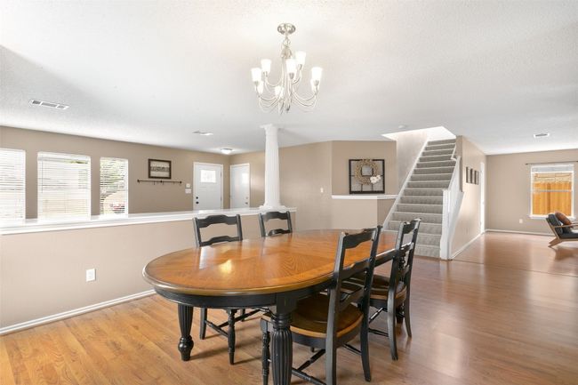 An elegant dining room featuring a chandelier, wood flooring, and a view of the second-story entry staircase. | Image 10