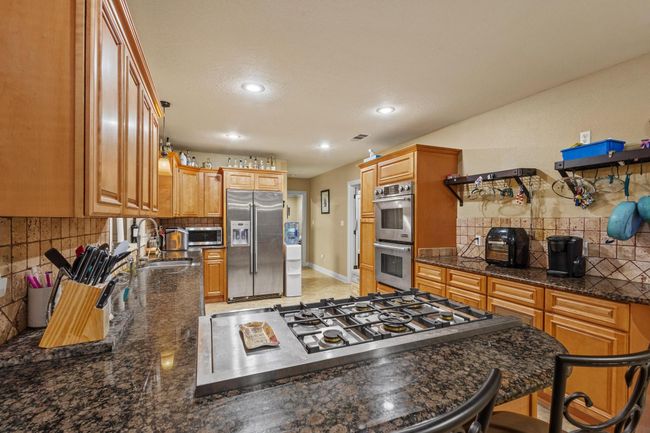 Kitchen with recessed lighting, stainless steel appliances, backsplash, a sink, and dark stone counters | Image 9
