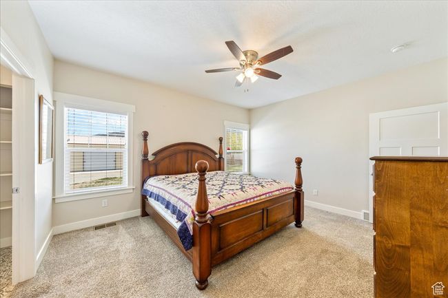 Bedroom featuring light carpet, baseboards, visible vents, and a ceiling fan | Image 22