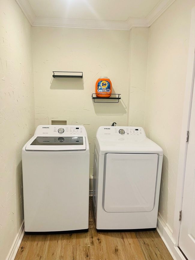 Laundry room featuring separate washer and dryer, crown molding, and light wood-type flooring | Image 23