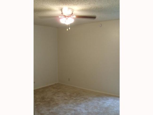 Carpeted empty room featuring a ceiling fan, a textured ceiling, and baseboards | Image 6