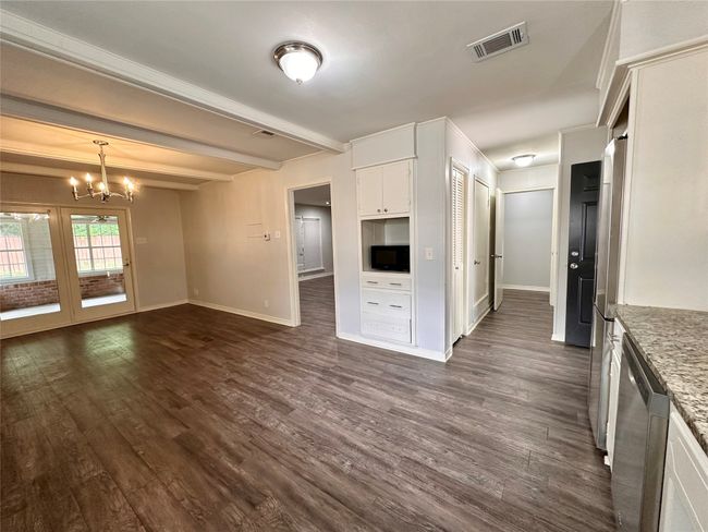 Kitchen with dishwasher, black microwave, a chandelier, dark wood-style flooring, and white cabinetry | Image 15