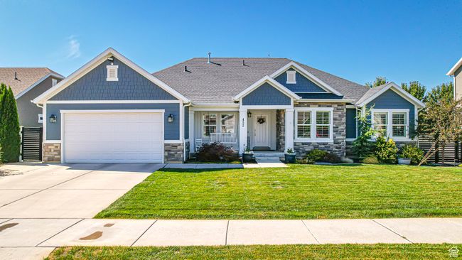 Craftsman-style home with driveway, a front yard, stone siding, roof with shingles, and a garage | Image 69