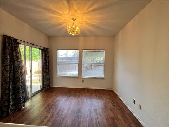 Empty room featuring a chandelier, wood finished floors, and baseboards | Image 5