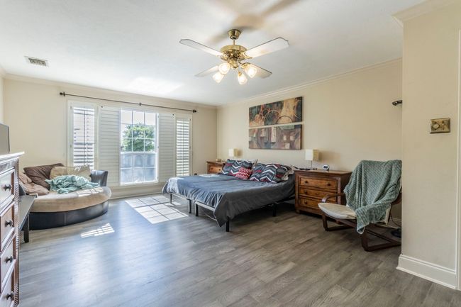 Bedroom with wood finished floors, ornamental molding, baseboards, and a ceiling fan | Image 11