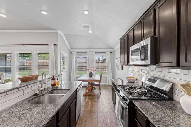 Kitchen with stainless steel appliances, lofted ceiling, dark wood-style flooring, dark brown cabinetry, and decorative backsplash | Image 28