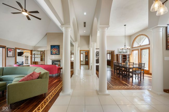 interior space with visible vents, high vaulted ceiling, a glass covered fireplace, and ornate columns | Image 8