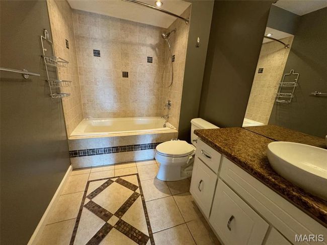 hall bathroom featuring tile patterned flooring, vanity, tiled shower / bath combo, and toilet | Image 28