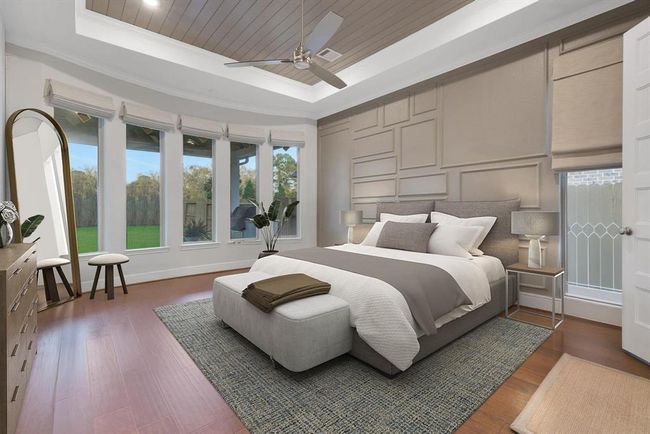 The modern primary bedroom with a spacious layout. It features a stylish textured accent wall, and abundant natural light from a row of tall windows. The room is enhanced with a ceiling fan, wood flooring, and customer wood work on the ceiling. | Image 27