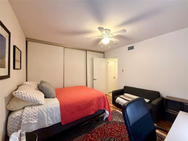 Bedroom with wood finished floors, visible vents, ceiling fan, and a closet | Image 14