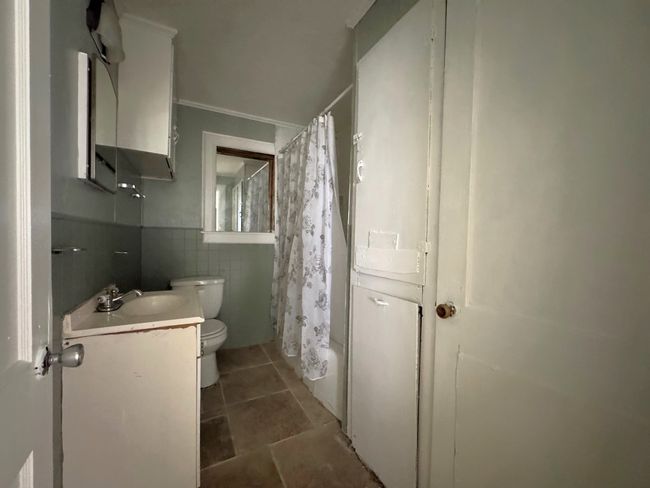 Bathroom featuring vanity, tile walls, shower / bath combination with curtain, crown molding, and wainscoting | Image 8