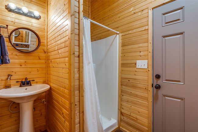 Bathroom with wood walls and curtained shower | Image 9