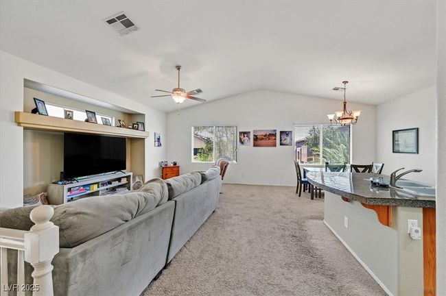 Living area featuring vaulted ceiling, a chandelier, light colored carpet, and ceiling fan | Image 12