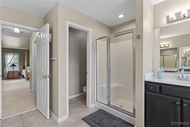 Full bathroom featuring a shower stall, vanity, tile patterned floors, toilet, and visible vents | Image 30