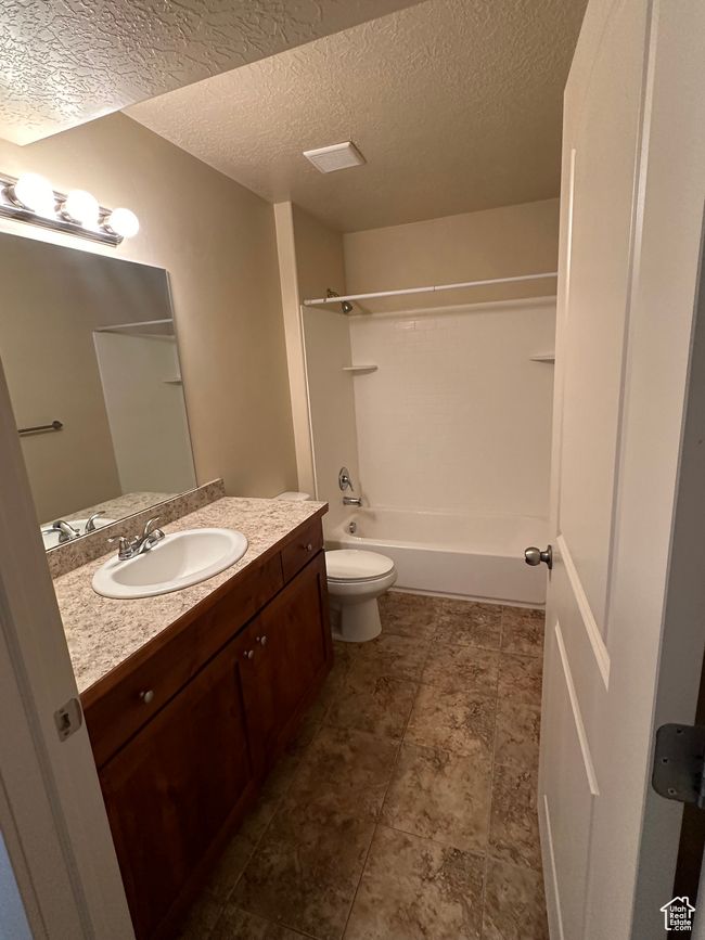 Full bath with toilet, washtub / shower combination, a textured ceiling, and vanity | Image 16