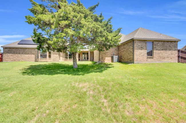 Back of property featuring brick siding, a shingled roof, a lawn, and solar panels | Image 37