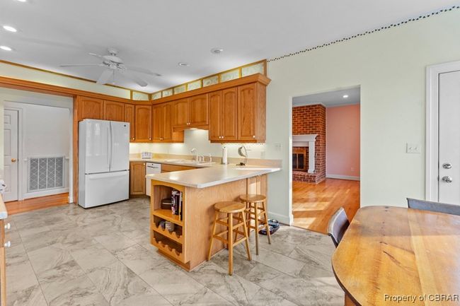 Kitchen with white appliances, light countertops, ceiling fan, a peninsula, and a kitchen breakfast bar | Image 23