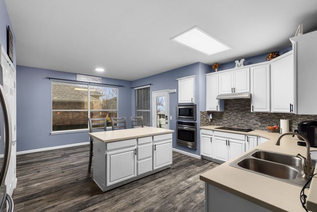Kitchen featuring white cabinetry, a center island, sink, tasteful backsplash, and appliances with stainless steel finishes | Image 14