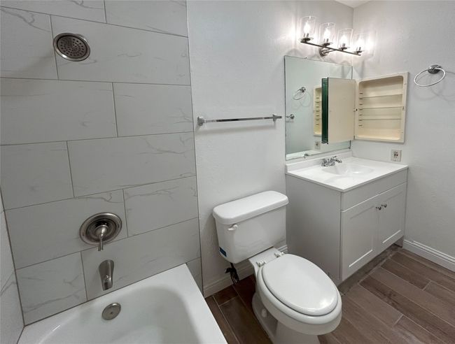 Full bathroom featuring toilet, vanity, a notable chandelier, tiled shower / bath and medicine cabinet | Image 28