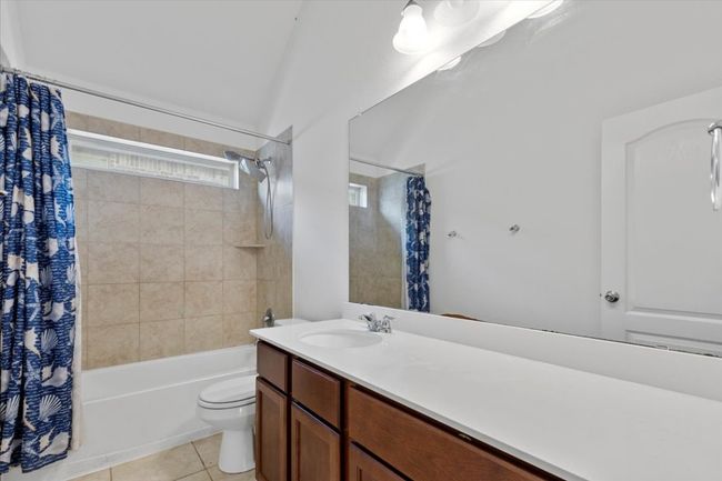 Bathroom featuring toilet, vanity, tile patterned floors, and shower / bath combo with shower curtain | Image 23