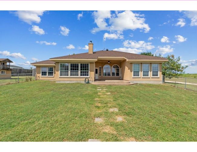 Back of property with ceiling fan, a patio area, a chimney, and stucco siding | Image 28