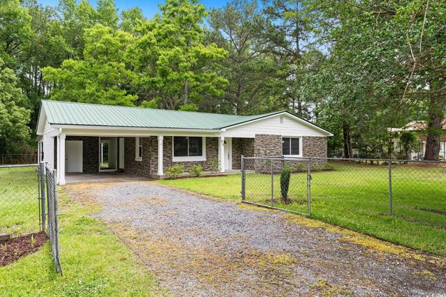 Ranch-style house featuring driveway, stone siding, metal roof, a carport, and a gate | Image 4