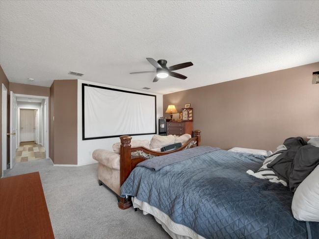 Bedroom with ceiling fan, a textured ceiling, and light carpet | Image 17