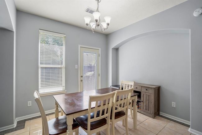 This close-up of the breakfast area showcases a recessed arch that creates the perfect nook for a buffet or display cabinet—adding both style and function without sacrificing space. A large window fills the room with natural light, and the nearby back door offers easy access to the patio for seamless indoor-outdoor living. | Image 16