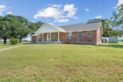 Single story home featuring a front lawn and a storage unit | Image 1