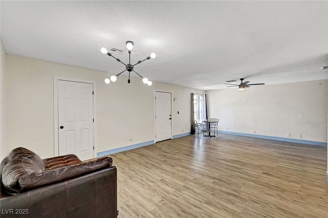 Unfurnished living room with a chandelier, light wood-type flooring, and a ceiling fan | Image 8