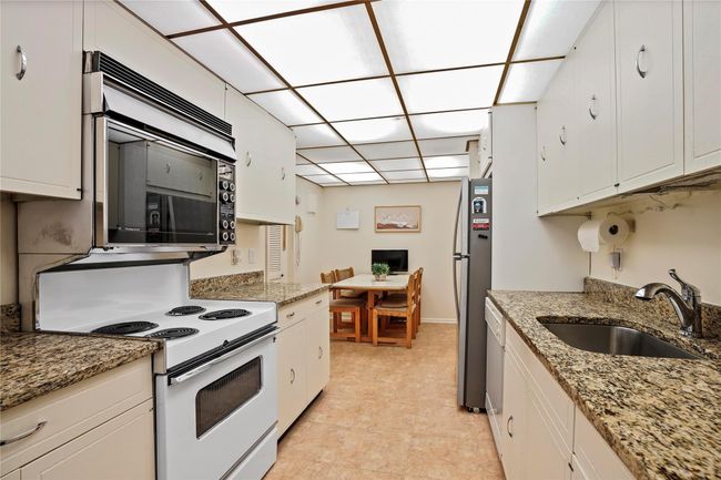 Kitchen featuring light stone countertops, white cabinets, appliances with stainless steel finishes, and sink | Image 11