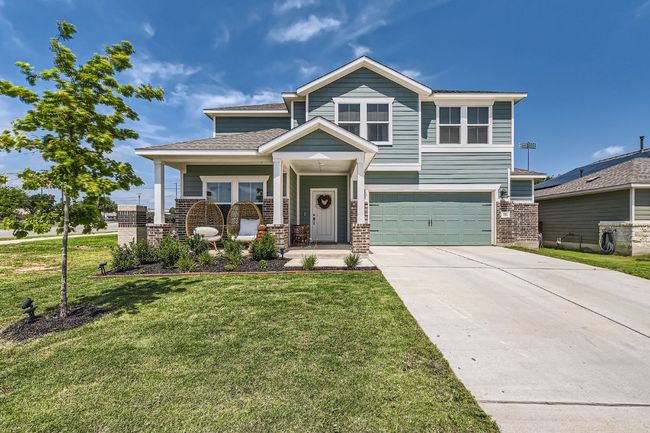 View of front facade featuring an attached garage, concrete driveway, a porch, a front yard, and brick siding | Image 4