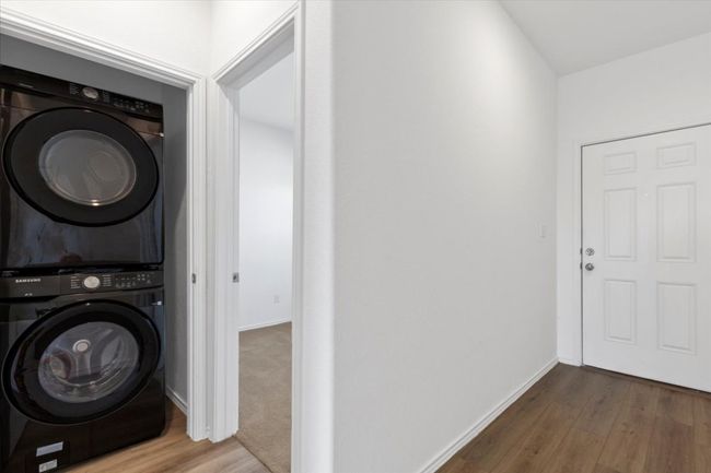 Washroom featuring estacked washer and dryer and wood finished floors | Image 15