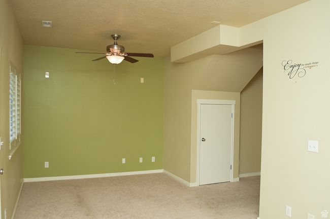 Empty room featuring ceiling fan, light colored carpet, baseboards, and a textured ceiling | Image 5