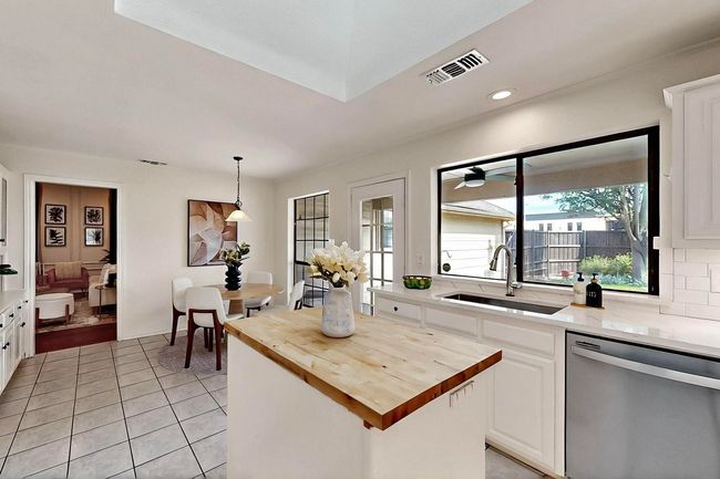 Kitchen with wood counters, stainless steel dishwasher, light tile patterned floors, recessed lighting, and white cabinetry | Image 9