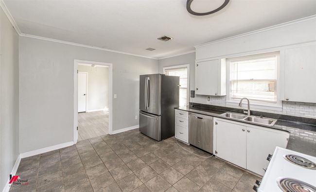 Kitchen with visible vents, crown molding, dark countertops, and appliances with stainless steel finishes | Image 12