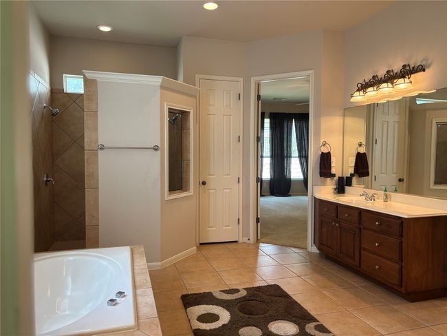 Bathroom with a tub to relax in, vanity, tile patterned flooring, and tiled shower | Image 13